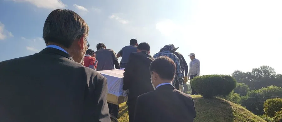 잔디 언덕길을 따라 관을 함께 옮기는 운구 행렬